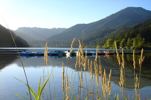 A calm lake with boats docked, surrounded by forested hills.
