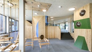 A modern interior with wooden climbing structures, a net bridge, and a staircase. - JUFA Hotel Erlaufsee (Mariazell)