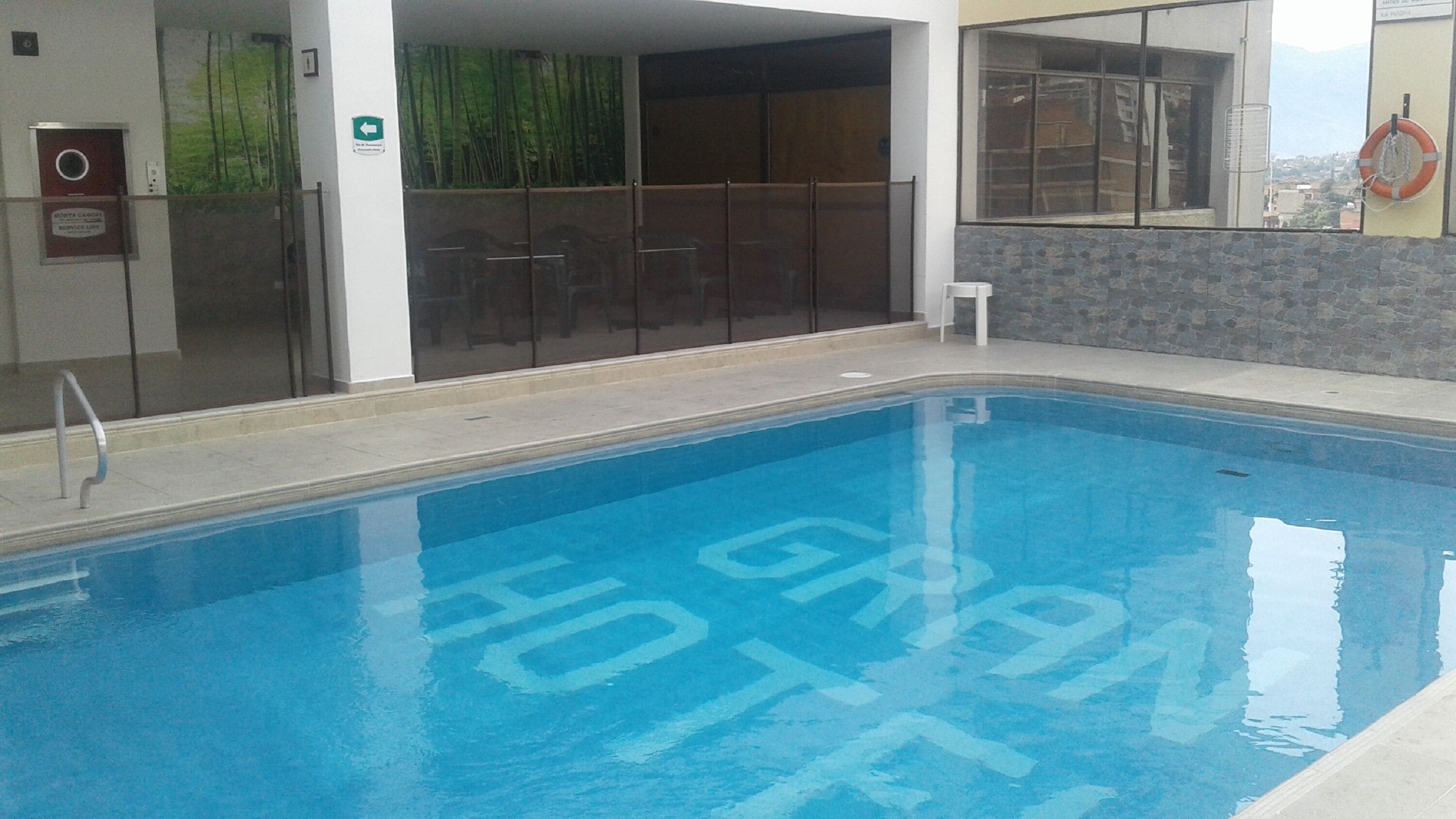 A swimming pool with a clear blue water surface and the words "GRAND HOTEL" written on the poolside.