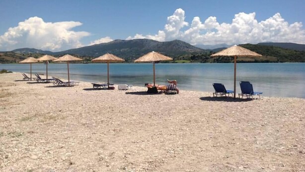 A beach with sun loungers and thatched umbrellas.