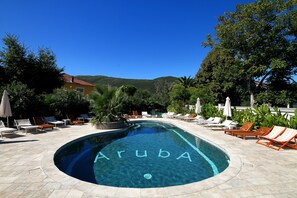 A swimming pool with the word "Aruba" written on the water, surrounded by lounge chairs and umbrellas. - Hotel Aruba (Lastva Grbaljska)