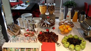Una mesa de bufé con diversos alimentos, como pasteles, frutas y salsas.