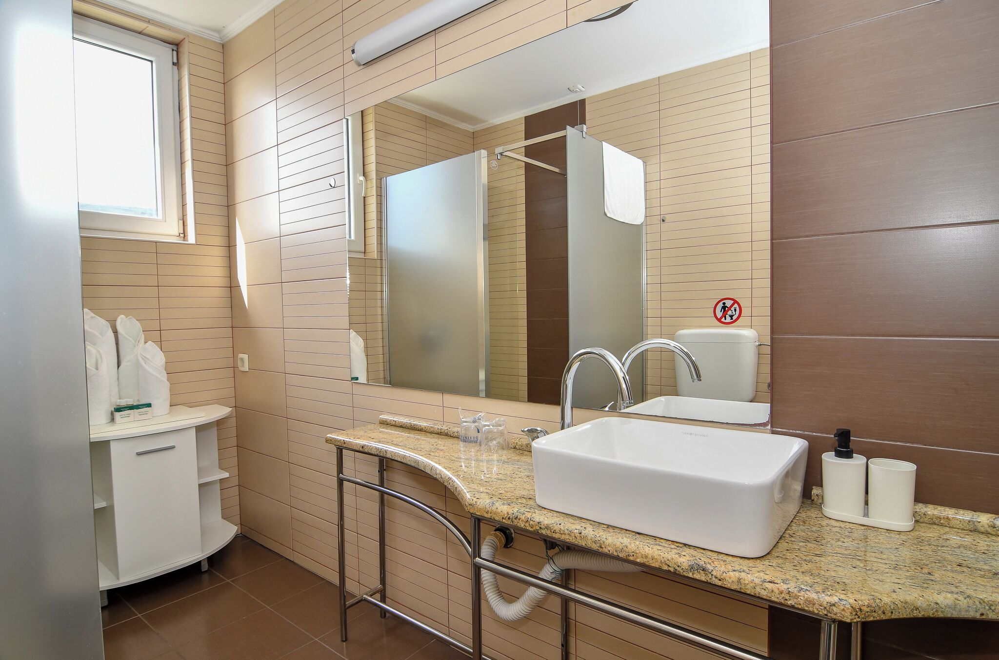 Een badkamer met een wit wastafelmeubel, een spiegel, een douche en een handdoekrek.