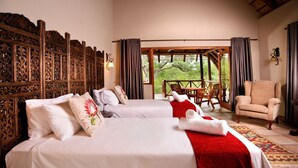 Een hotelkamer met twee bedden, een houten hoofdbord, een rode deken, een stoel en uitzicht op de omgeving.