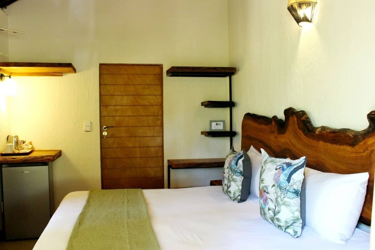 A hotel room with a bed, a wooden headboard, a bedside table, a lamp, and a door.