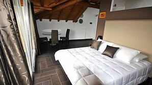 A bedroom with a bed, a table, and chairs in the background.