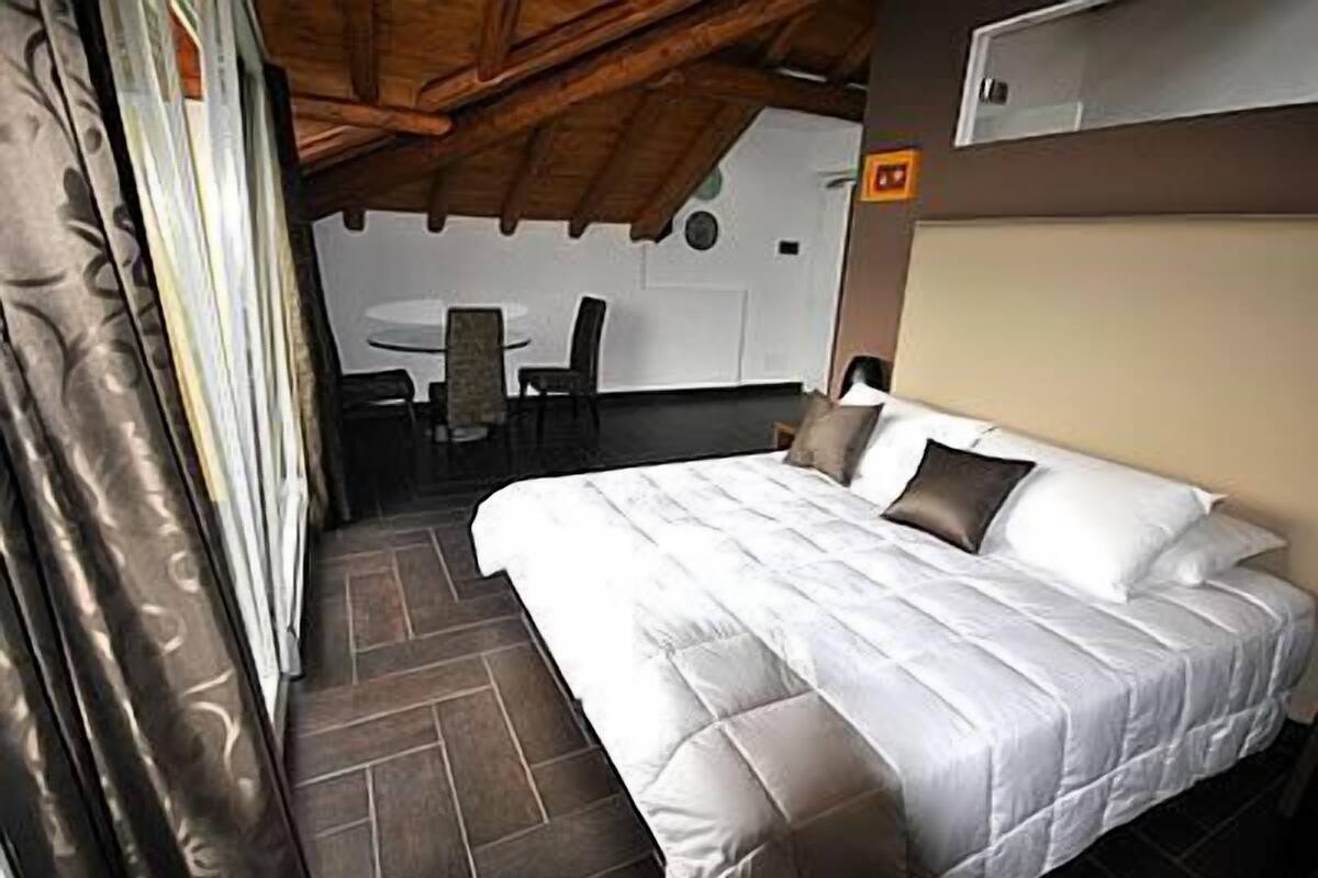 Une chambre à coucher avec un lit, une table et des chaises à l’arrière-plan.