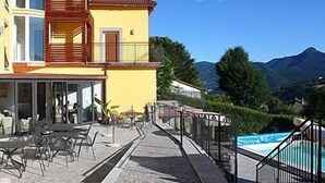 A two-story building with a balcony, outdoor seating area, and a pool.