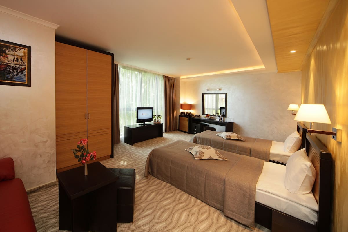 A hotel room with a bed, a desk, a television, a chair, and a painting on the wall.