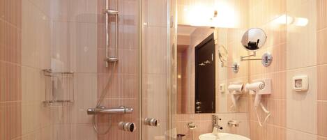 A modern bathroom with a glass-enclosed shower, a sink with a vanity, and a mirror with a hairdryer mounted on the wall.