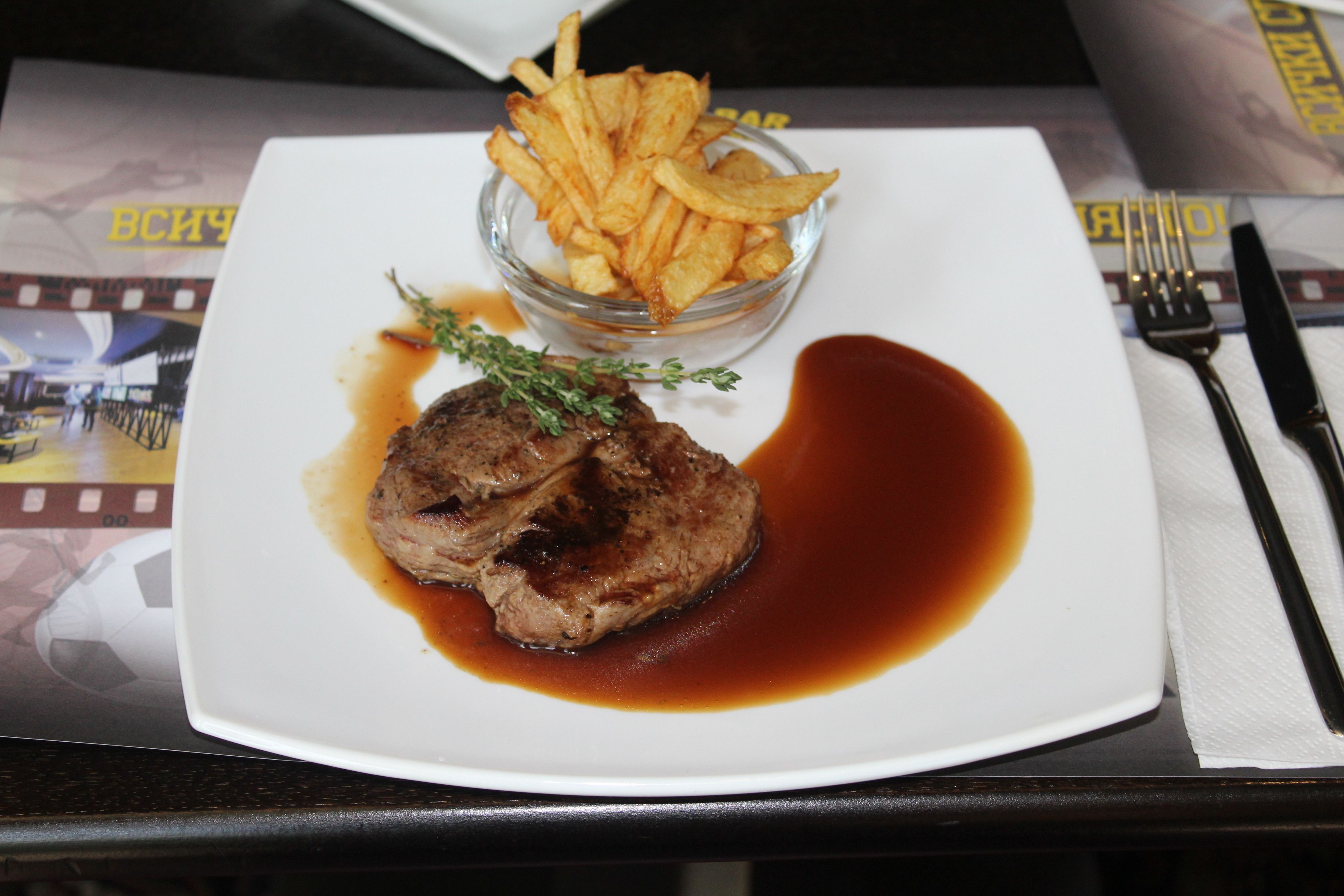 Een bord met steak en friet, een vork en een mes op een tafel.