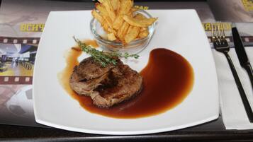 Een bord met steak en friet, een vork en een mes op een tafel.