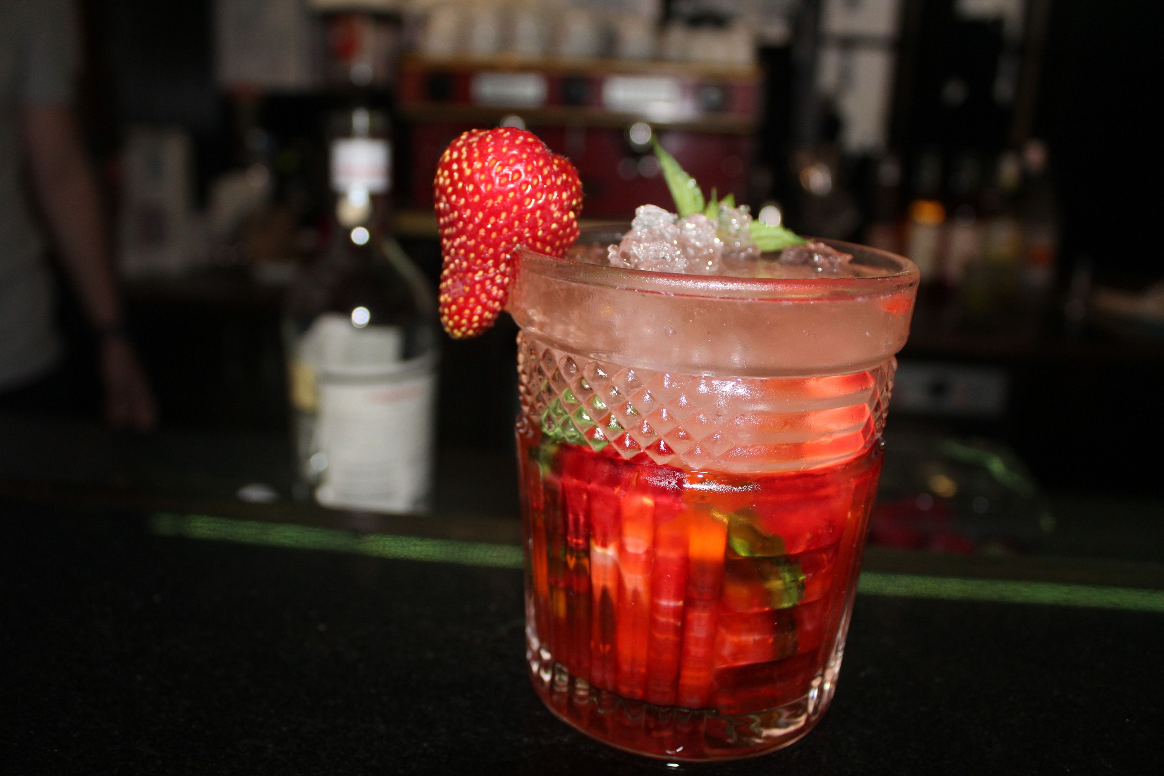 A cocktail with a strawberry garnish in a textured glass.