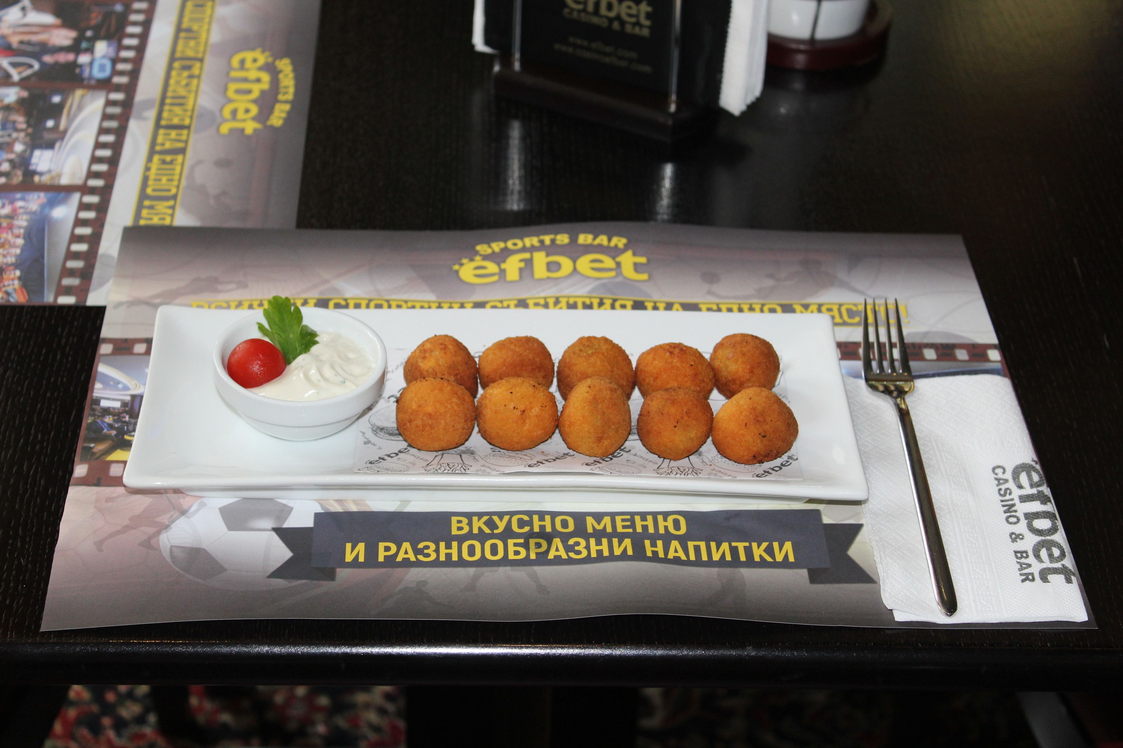 A table with a plate of food, a fork, and a menu.
