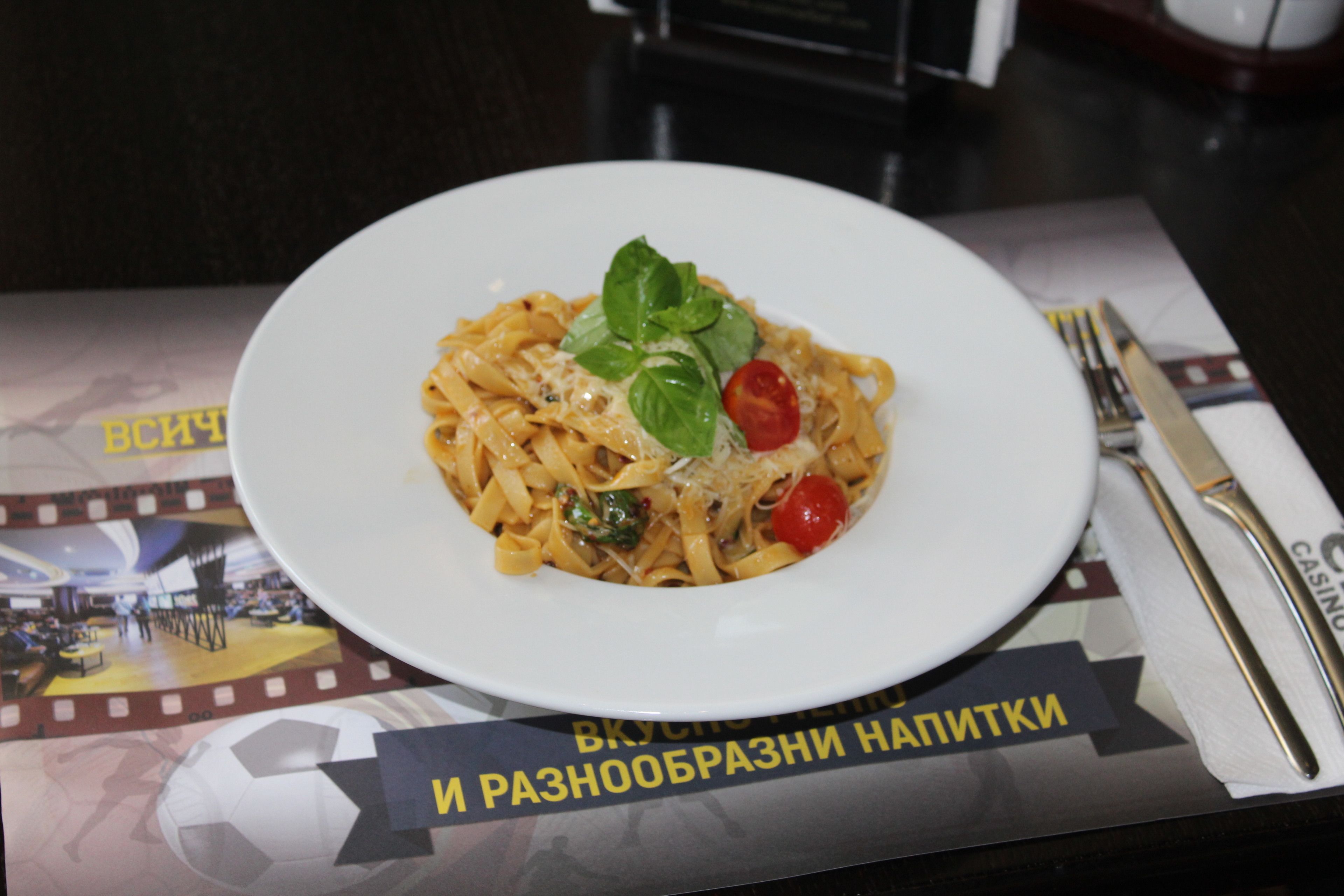 A plate of pasta with a fork and knife on a table with a film strip and text.