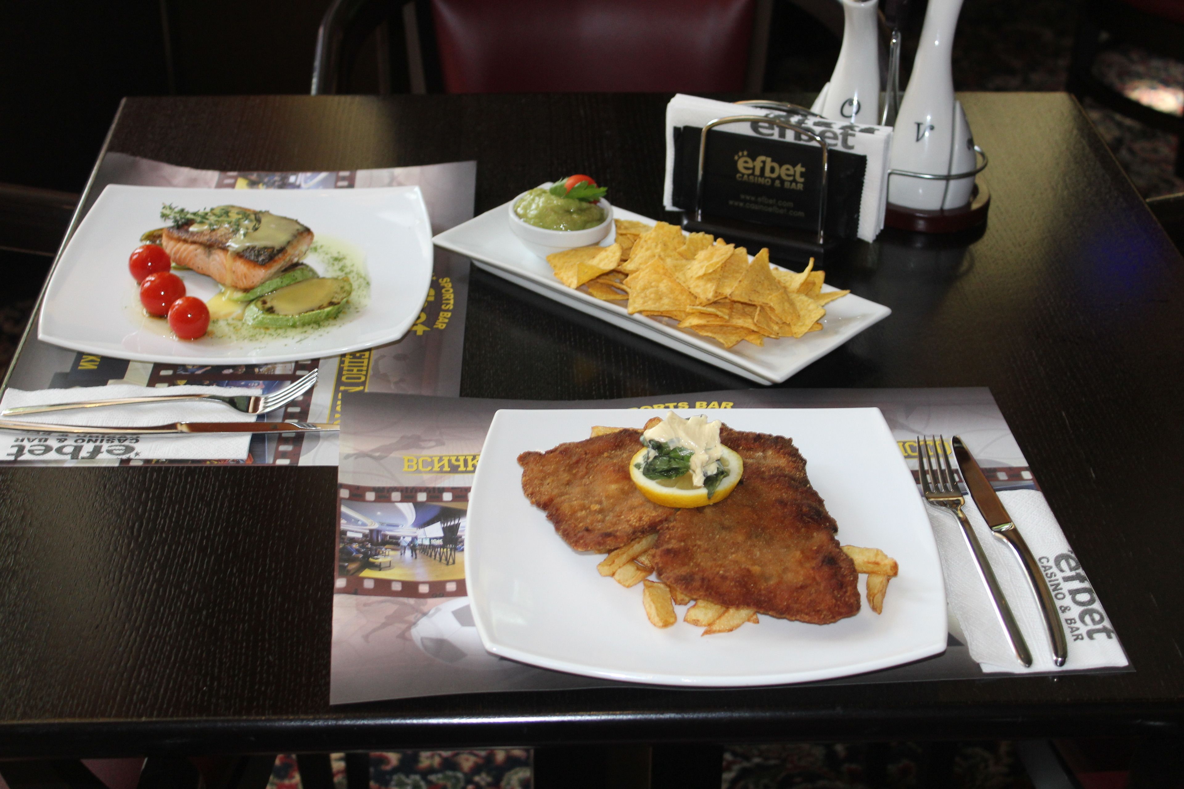 A table with a meal consisting of fish, chips, and a side of sauce.