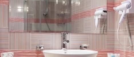 Un baño moderno con un espejo grande, una ducha con cerramiento de vidrio y un lavabo blanco.