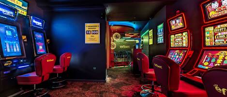 A casino interior with slot machines, red chairs, and a carpeted floor.