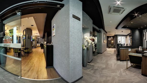 A modern hotel lobby with a reception desk, seating area, and a glass partition. - EfBet Hotel (Varna)