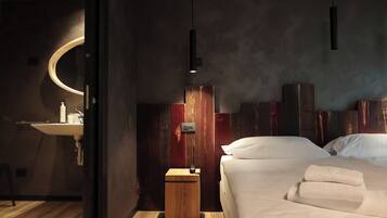 A modern bedroom with a wooden headboard, a bedside table, and a bed with white linens.