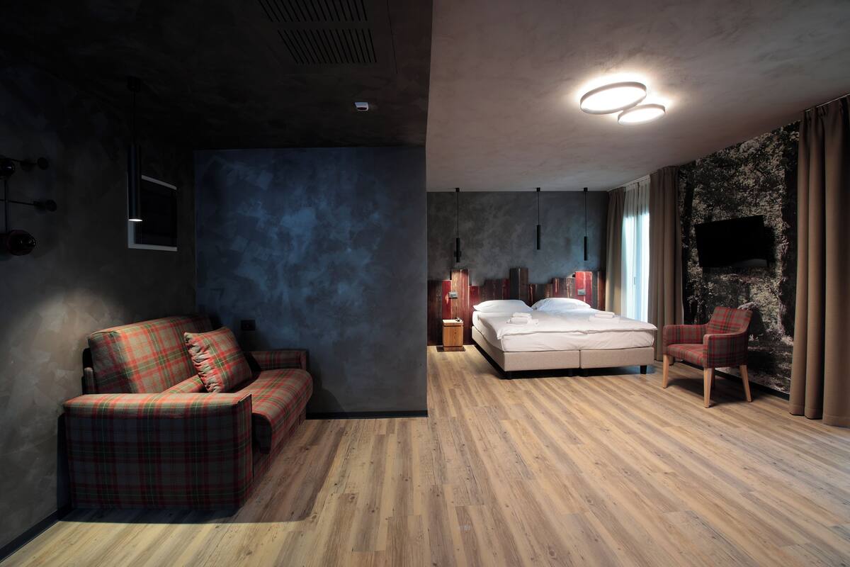 A modern bedroom with a large bed, a sofa, and a chair.