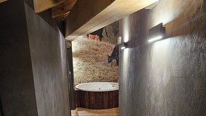 Un estrecho pasillo de madera con una estructura circular en el centro, posiblemente un área de descanso o un elemento decorativo.