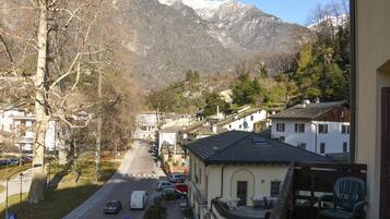 Una strada residenziale con case, cielo sereno e montagne sullo sfondo.