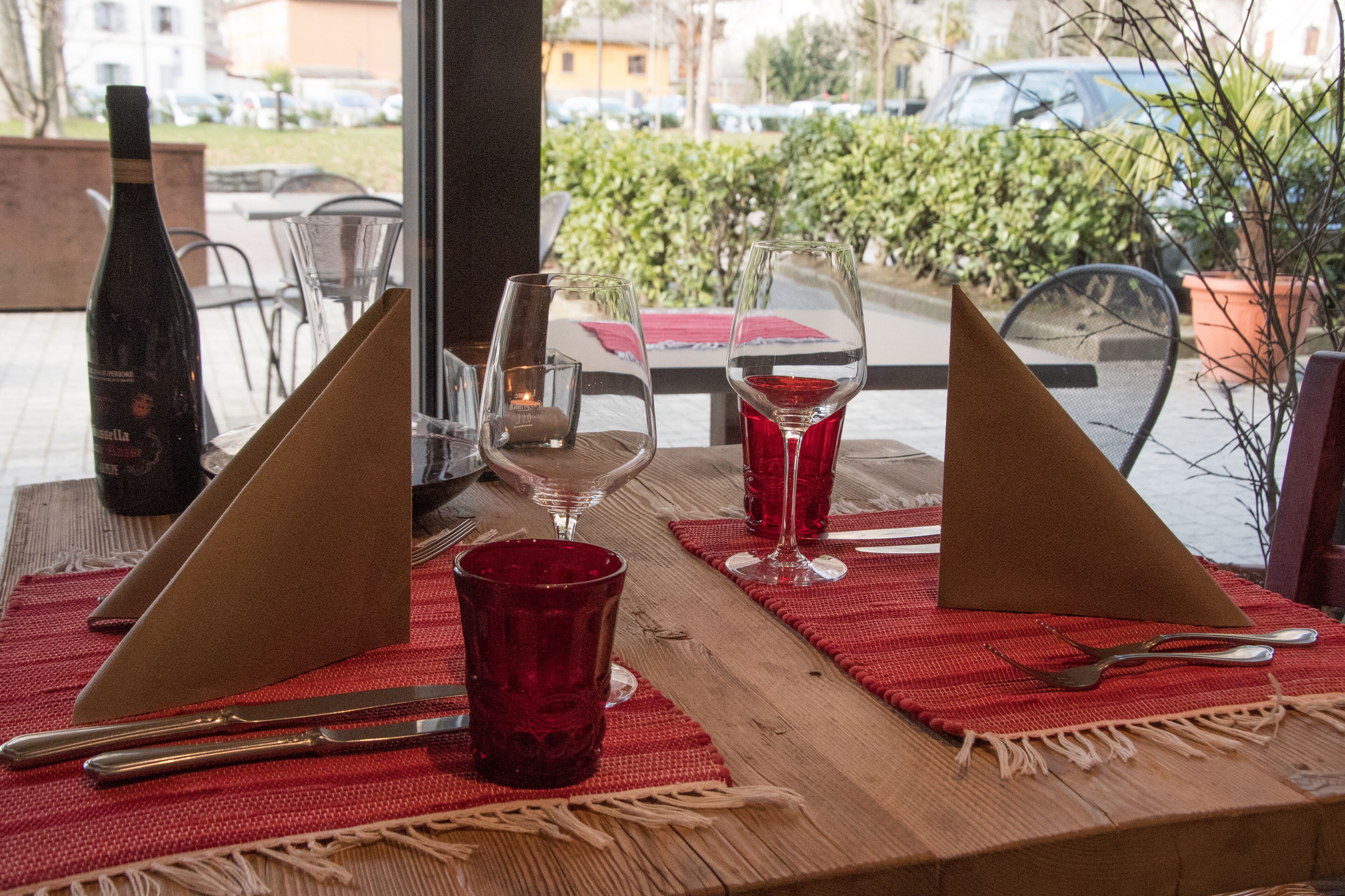 A table set with red napkins, wine glasses, and cutlery.