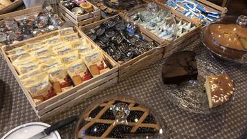A buffet table with various food items including Dorate cheese, pastries, and a pie.