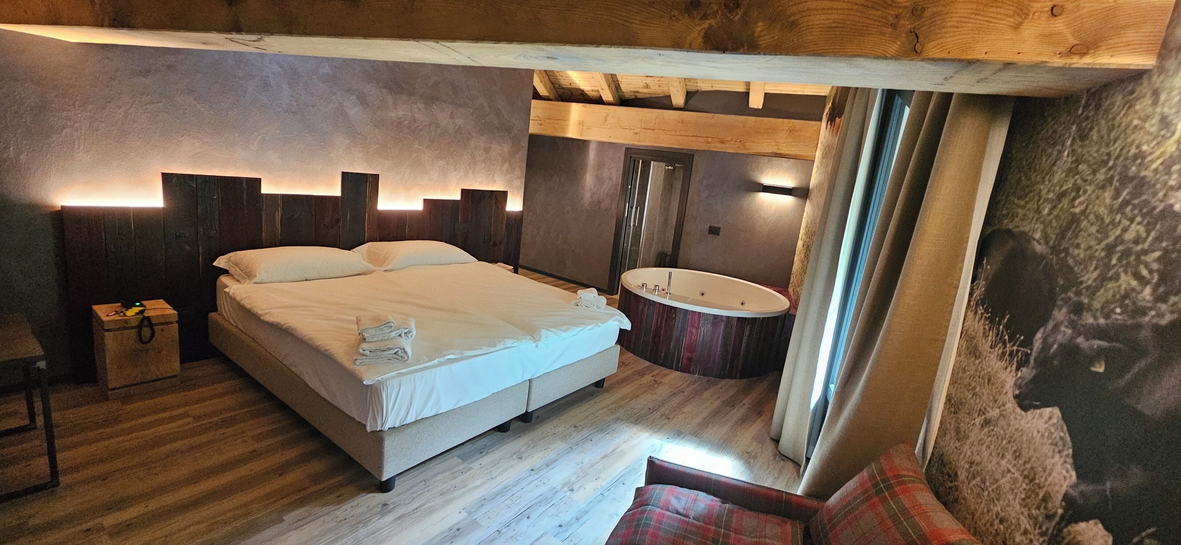 Una camera da letto con un letto, un pavimento in legno, una vasca da bagno tonda e un soffitto in legno.