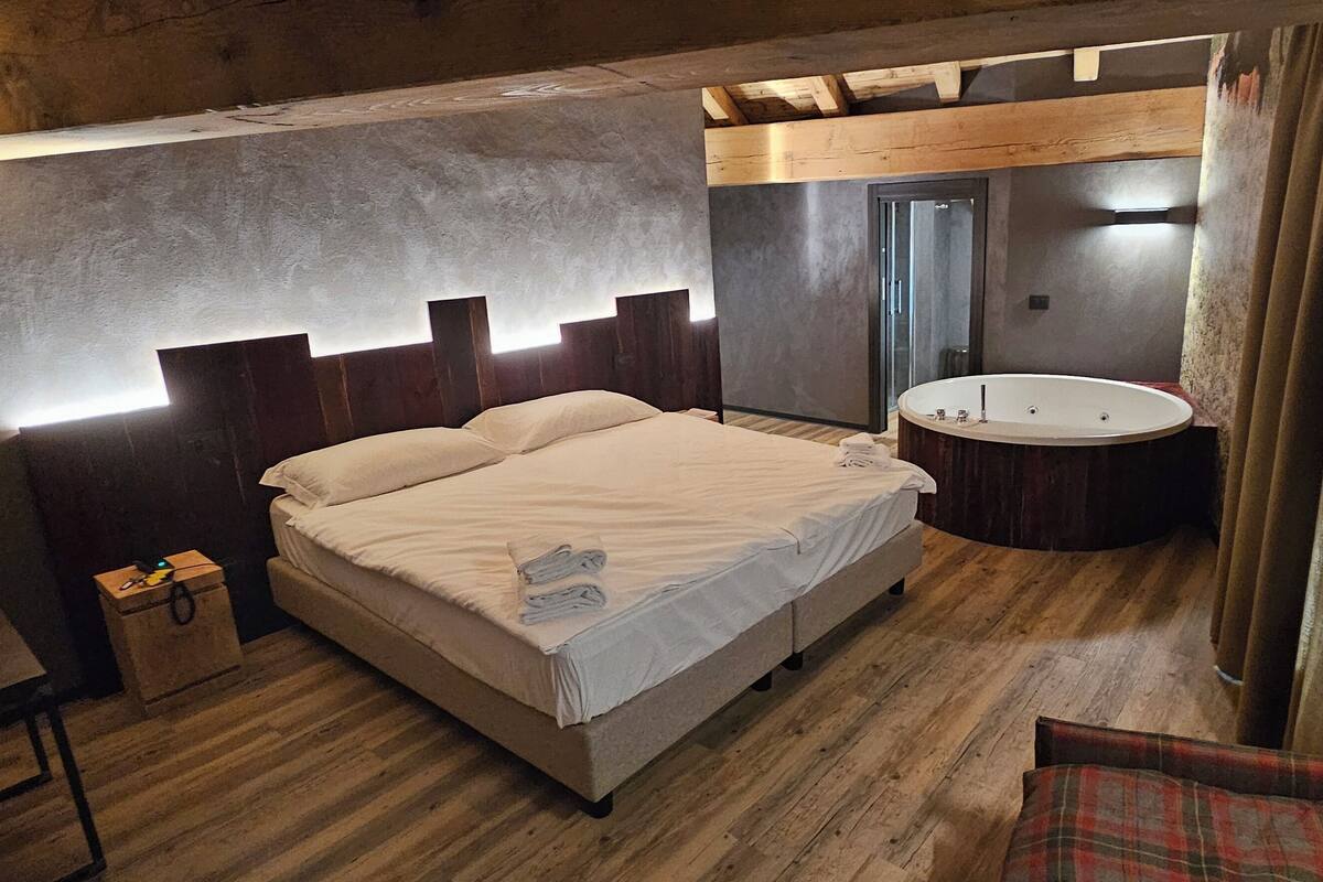 A bedroom with a bed, bedside table, and a round mirror.