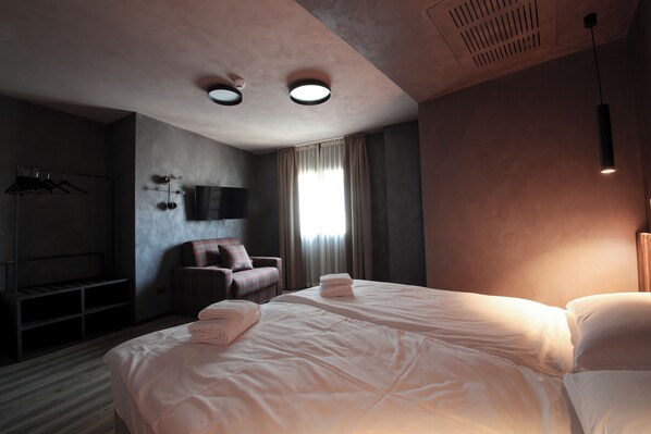 Una habitación de hotel con una cama grande, una silla, un televisor y un armario.