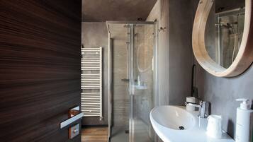 A modern bathroom with a glass shower enclosure, a white sink, and a wooden-framed mirror.