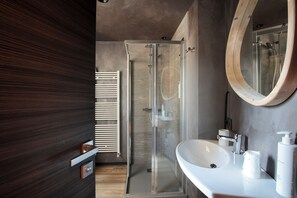 A modern bathroom with a glass shower enclosure, a white sink, and a wooden-framed mirror. - Crimea Wine Hotel (Chiavenna)