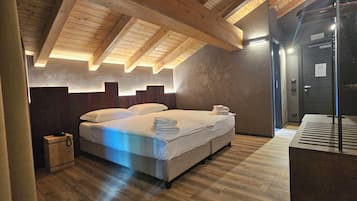 A modern bedroom with a wooden ceiling, a bed with white linens, and a dark door.