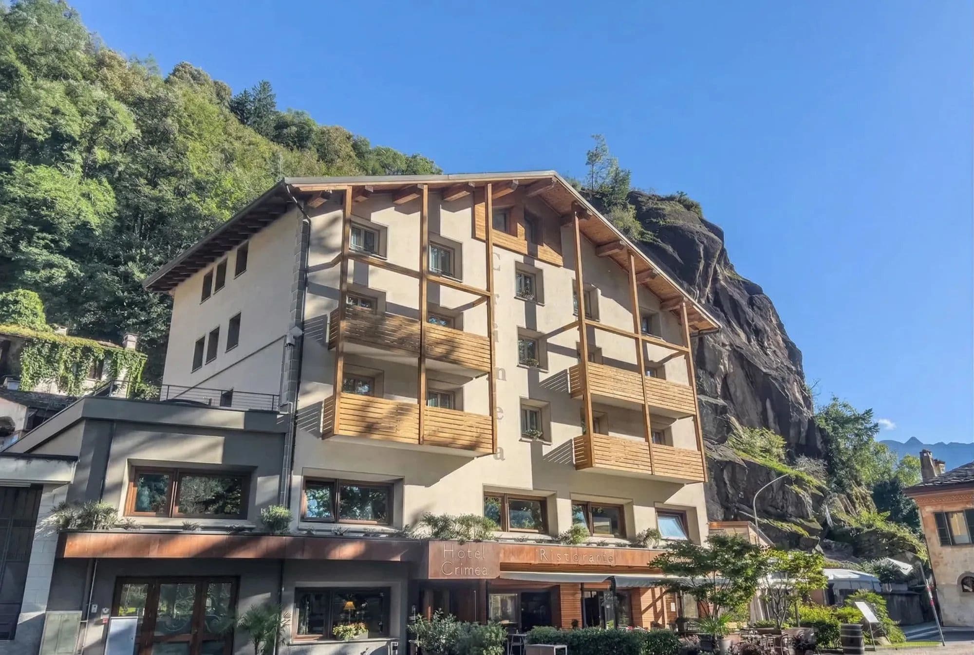 A multi-story hotel with balconies, a restaurant, and a view of a mountain.