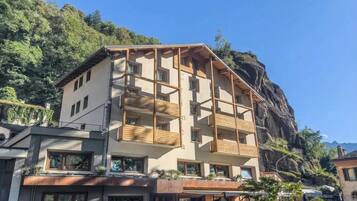 Un hôtel à plusieurs étages, doté de balcons, d’un restaurant et offrant une vue sur une montagne.