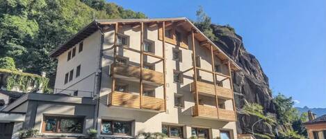 Un hôtel à plusieurs étages, doté de balcons, d’un restaurant et offrant une vue sur une montagne.