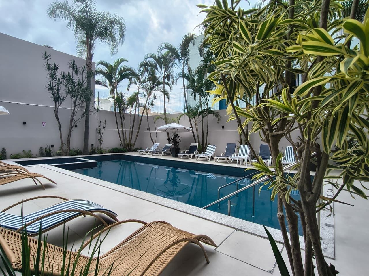 Una piscina al aire libre, sillones reclinables de piscina