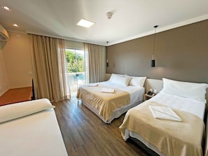 A hotel room with two beds, a balcony, and a view of greenery. - Das Nações Hotel (Florianópolis)