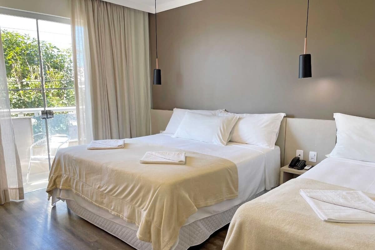 A hotel room with two beds, a balcony, and a modern design.