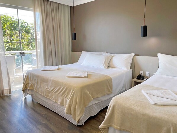 Habitación de hotel con dos camas, balcón y diseño moderno.
