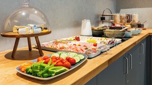 A buffet setup with various food items and a glass dome covering some dishes. - mk | hotel frankfurt (Frankfurt)