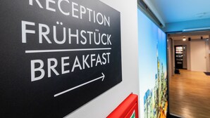 A sign indicating the direction to the reception and breakfast area. - mk | hotel frankfurt (Frankfurt)