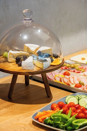 Una mesa de madera con una campana de cristal que muestra queso y uvas.