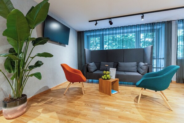 Una sala moderna con un sofá, dos sillones, una mesa de centro y una planta grande.