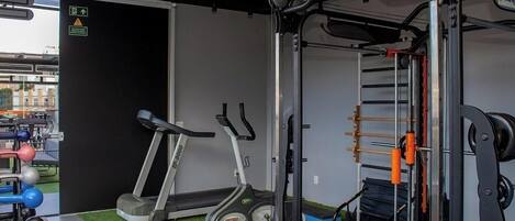 Un gimnasio con equipo de ejercicio, cinta de correr y soporte para pesas.