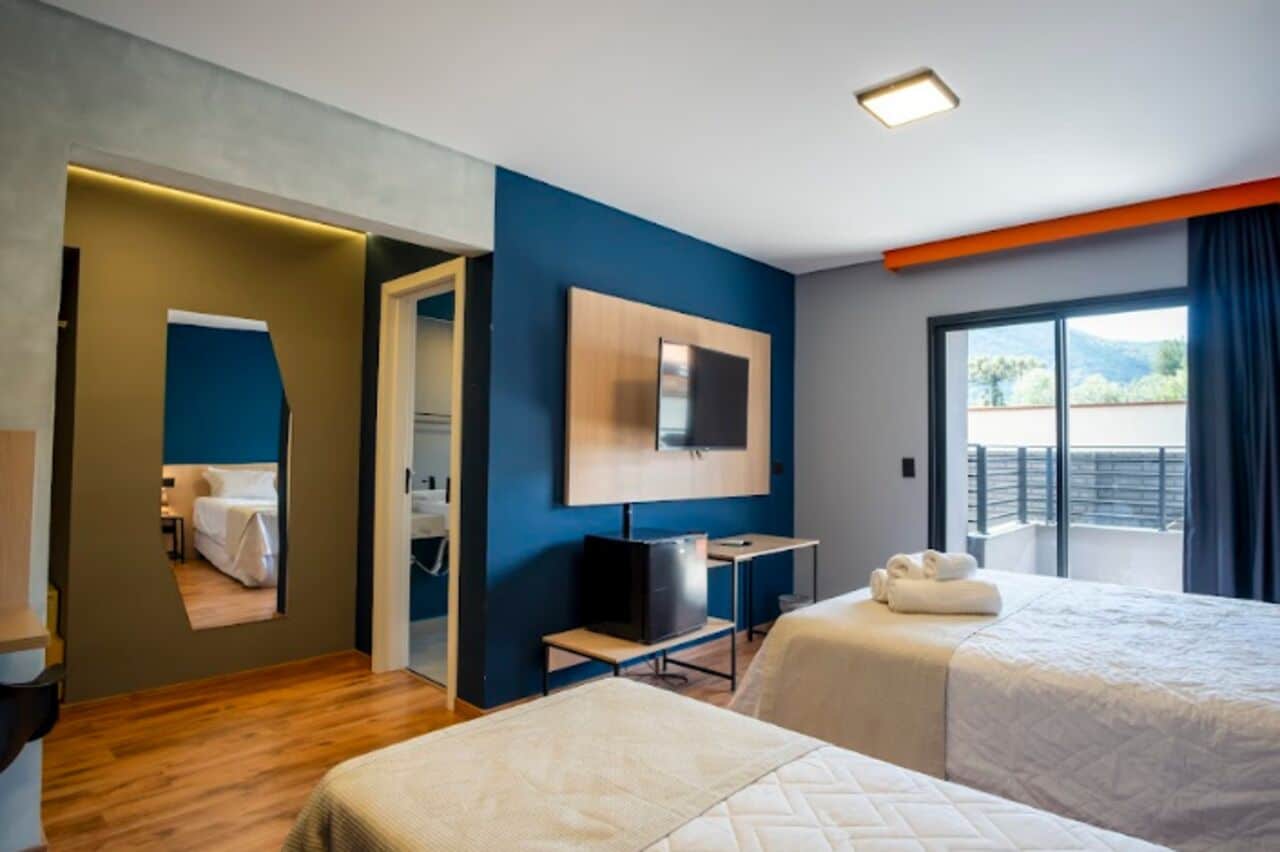 Ein Hotelzimmer mit zwei Betten, einem Fernseher, einem Schreibtisch und einem Balkon mit Blick.