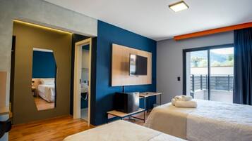 Ein Hotelzimmer mit zwei Betten, einem Fernseher, einem Schreibtisch und einem Balkon mit Blick.