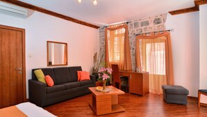 A modern living room with a sofa, coffee table, and a stone accent wall. - Hotel Villa Nora (Hvar)